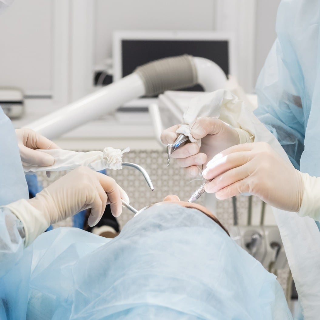 Close-up of the hands of a dentist and nurse surgeon over an operating room during a dental implant operation